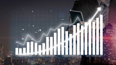 Bir işadamı gece kentsel bir arazide duruyor, bir tablette gösterilen büyüme eğilimlerini analiz ediyor, başarı ve ilerlemeyi temsil eden bar ve çizgi grafikleri sunuyor. Copula