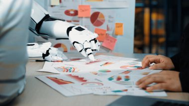Robotik bir el, çağdaş bir ofiste, yapay zeka teknolojisinin veri analizi ve iş kararlarına entegrasyonunu gösteren basılı çizelge ve grafiklere yazar.