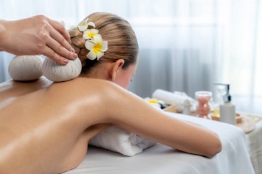 Sıcak bitkisel top spa masaj vücut tedavisi, masör kadın vücuduna nazikçe şifalı bitki torbası bastırıyor. Aromaterapi dinlenme sükuneti ve sükuneti kaplıca salonundaki atmosferi aydınlatıyor. Sessiz.