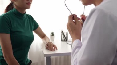 Hasta klinikte ya da hastane ofisinde doktor randevusuna gidiyor. Hastaların risk faktörünü tespit etmek için nabzını ölçmek için steteskopla doktor muayenesi ve teşhis semptomları. Ağır çekim. Katı.