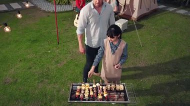 Aile birlikte bahçede kamp kurar, baba ve kız aile bireyleri için ızgara yapar. Doğayla iç içe olmak için açık hava kamp aktiviteleri ve genç nesil çapraz kuşaklarla zaman geçirmek için. Uyumsuzluk.