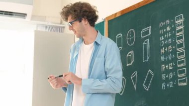Kafkas öğretmeni tahtada dururken öğrenciye bakıyor. Profesyonel eğitmenin öğrettiği düşük açılı kamera ve çeşitli öğrencilerin sorularına cevap verirken matematik teorisini açıkla. Pedagoji.