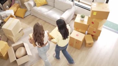 Oda arkadaşı kanepede otururken ve otururken yürürken ve kutu taşırken. Oturma odasındaki kanepede dinlenirken yeni eve taşınan güzel çiftin manzarası kutu ve mobilyalarla çevrili. Myrmidon.