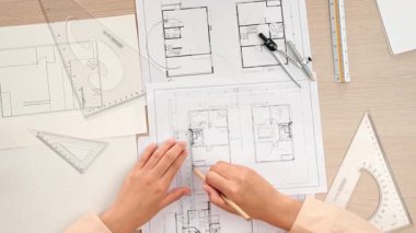 Akıllı mimar ya da akıllı mühendisin ölçüm aracı ve kalem el kullanarak mimari ofisindeki inşaat isabet planı üzerine detaylı bir yazı yazışının videosu. Eline odaklan. - Yakın çekim. Tanımlama.