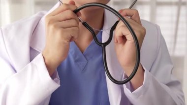 Hasta klinikte ya da hastane ofisinde doktor randevusuna gidiyor. Hastaların nabzını steteskopla kontrol edip risk faktörünü belirleyen doktor semptomları inceliyor. Ağır çekim. Katı.