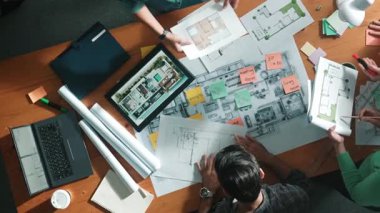 Planı elinde tutan inşaat mühendisi ekibinin en iyi görüntüsü ve dizüstü bilgisayar, proje planı ve planıyla masada duruyor. Yapışkan notları planlayan ve yazan yetenekli proje yöneticisinin havadan görünüşü. Sempozyum.