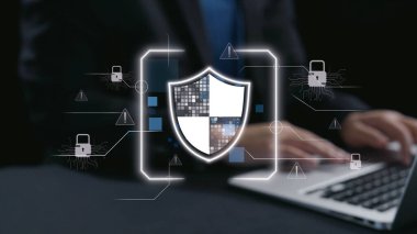 Kalkan grafikli dijital güvenlik kavramını sergileyen modern bir ofis, potansiyel risk ve tehditlere karşı veri korumanın önemini vurguluyor. Dörtgen