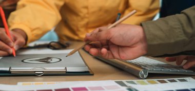 Canlı, işbirlikçi bir çalışma alanı, çeşitli ellerin yaratıcı tartışmalara katıldığını gösteriyor. Renk örnekleri ve tasarım kağıtları takım çalışmasının ve ilhamın yenilikçi atmosferini yansıtır. SACTR