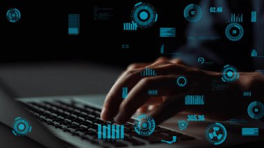 Bir dizüstü bilgisayarın klavyesine yazı yazan bir elin yakın plan görüntüsü, koyu bir arkaplan karşısında mavi dijital grafikleri ve veri görsellerini gösterir. Xenic