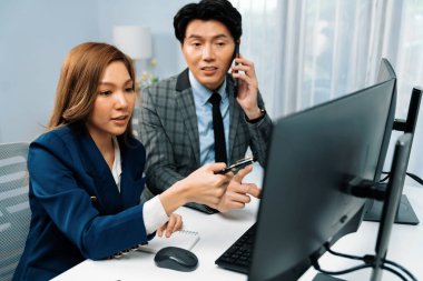 İş ortağıyla cep telefonundan arayan işadamı bilgisayardaki kadın iş arkadaşıyla hisse senedi değer veri tabanını hesaplarken şirket değerini analiz ediyor ya da güncel alım yapıyor. İnfobahn.