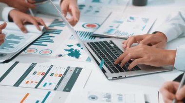 Bir iş toplantısında yer alan, verileri analiz eden ve modern bir ofis ortamında dijital cihazlar ve evrak işleriyle işbirliği yapan profesyonellerin dinamik bir sahnesi. SACTR