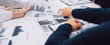 Bir grup profesyonel, etkili iş stratejileri ve karar verme mekanizmaları hakkında bilgi edinmek amacıyla çeşitli veri çizelgeleri ve grafikleri analiz ederek bir takım toplantısında işbirliği yapıyor. SACTR