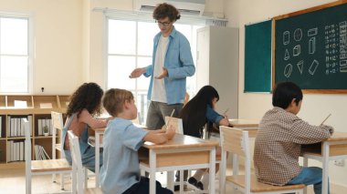 Öğrenci ödevlerine bakarken sınıfta yürüyen yetenekli bir öğretmen. Sınav yaparken ya da sınıfta ödev yaparken akıllı çocuk defterini kontrol eden profesyonel bir eğitmen. Pedagoji.