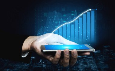 Akıllı telefonu tutan bir el, modern bağlamda finans ve teknolojideki başarıyı ve yeniliği sembolize eden dijital büyüme grafiğini gösterir. Etki