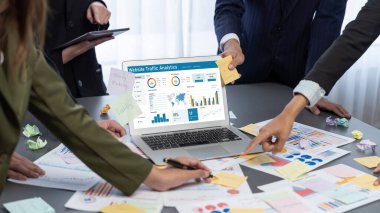 Analizci ekibi yaratıcı ve analitik beyin fırtınası fikri için bilgisayar ekranında BI veri paneli olan yapışkan bir not kullanıyor. Pazarlama stratejisi için finansal veri görselleştirme teknolojisini analiz et. Dahi.