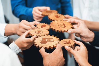 Değişik ellerin ahşap dişlileri tutmasını gösteren dinamik bir görüntü, her biri iş birliğini, yeniliği ve iş çözümlerini sembolize eden farklı ikonlar içeriyor. Dostluk