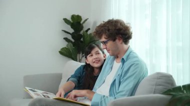 Beyaz bir baba ve tatlı bir kız kanepede otururken masal kitabı okuyorlar. Mutlu bir baba, sevimli bir Amerikan çocuğuna, birlikte zaman geçirirken hayal gücünün gelişmesi için hikaye anlatıyor. Pedagoji.