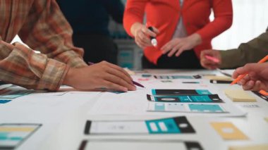 Bir grup profesyonel, dijital cihazlar ve geleneksel kağıt araçlardan yararlanarak kullanıcı arayüzü tasarım kavramlarını tartışarak yaratıcı bir toplantıya girişiyor. SACTR