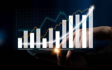 Çeşitli grafik ve grafikleri gösteren, mali analizleri ve iş büyüme kavramlarını görsel veriler yoluyla temsil eden dijital bir aygıtı tutan ellerin yakın çekim görüntüsü. Etki