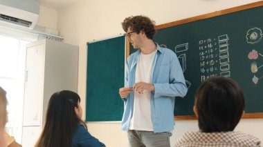 Matematik formülü veya teorisi ile karatahtanın önünde dururken sınıfın etrafına bakan profesyonel akıl hocası. Çeşitli ilköğretim öğrencileri matematik dersinde öğreniyor, çalışıyor ve oturuyor. Pedagoji.