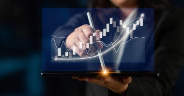 Bir iş analisti, çağdaş bir ofis ortamında mali eğilimleri ve veri analizlerini vurgulayan bir dizüstü bilgisayarda dijital büyüme grafiği gösteriyor. Etki