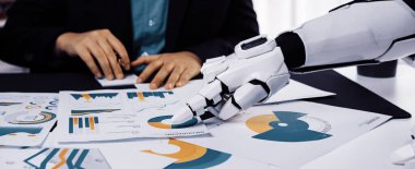 Bir robot el, bir masanın üzerindeki çizelge ve grafikleri analiz ediyor ve profesyonel bir ofiste teknolojinin ve insan işbirliğinin entegrasyonunu gösteriyor.