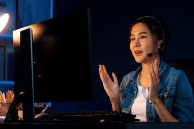 Sunucu kanalı Asyalı etkileyicisi canlı yayında konuşuyor. Sosyal medyada kulaklık takıyor, bilgisayar kaydı yapıyor, dinleyicileri selamlıyor ve Neon Modern Stüdyoları 'nda online olarak koçluk yapıyor. Taktik.