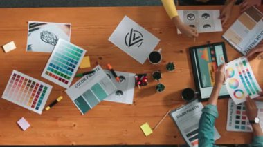 Proje yöneticisi renk paletleri seçerken tasarımcının tablete baktığı yukarıdan aşağıya hava görüntüsü. Profesyonel grafik tasarımının en üst görüntüsü ve logoya bakın. Yetenekli ekip grafikleri seçiyor. Sempozyum.