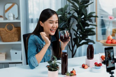 Gülümseyen, güzel Asyalı genç, lezzetli karışık çilek ve kiraz suyu detoksu içeceklerini inceleyen, sosyal medyada özel promosyon satışı için sağlıklı ürünler sergileyen. Taktik.