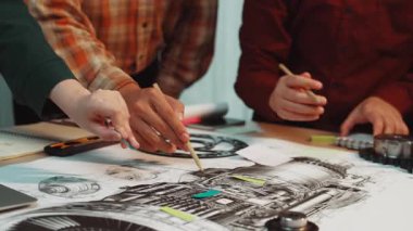 Mühendisler, modern bir çalışma alanında takım çalışması ve tasarım sürecindeki yaratıcılığı vurgulayarak, teknik çizimleri tartışırken görülüyor. SACTR