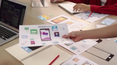 Mobil uygulama için kullanıcı arayüzü prototipini ofis çalışanlarına sunan harika bir şirket çalışanı. UX UI tasarımcısı kağıt üzerinde simge tasarımının işlevini açıklıyor. Sinerjik