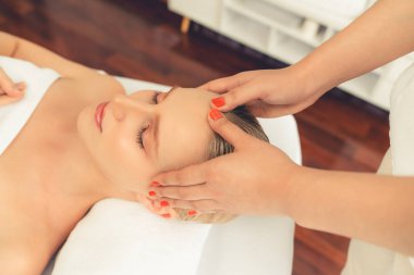 Kafkasyalı kadın stres önleyici kafa masajından ve lüks tatil beldesi ya da otel spa salonundaki modern ışık ortamında yüz güzelliği eğlencelerini şımartmaktan hoşlanıyor. Sessiz.
