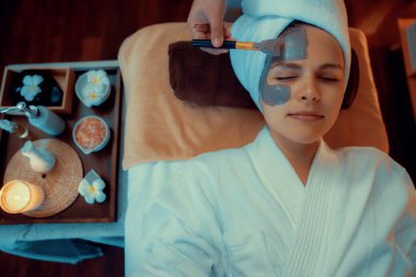 Kaplıca salonunun sakin atmosferi, üst düzey kadın müşteri sıcak mum ışığında kömür kömürü yüz kremi masajıyla kendini yenilemeye çalışıyor. Yüz bakımı ve güzellik konsepti. Sessiz.