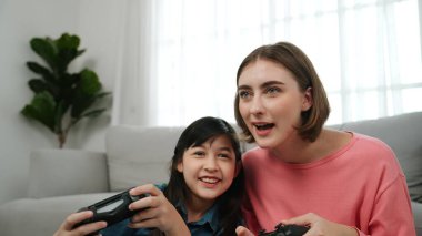 Kafkas anne ve kızı oturma odasında oturup oyun oynuyorlar. Mutlu anne, elinde joystick tutarken akıllı Asyalı kızla vakit geçiriyor. Oyun oynamaktan zevk alıyor. Yaşam tarzı konsepti. Pedagoji.