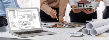 İç mimar tasarımcı grubu, daha kesin tasarım için planlar ve dizüstü bilgisayar ekran mimari yazılımı üzerinde birlikte tartışıyorlar. Modern ev tasarımı ve yenileme. İçgörü