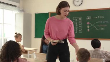 Profesyonel mutlu öğretmen sınıfta otururken sevimli bir öğrenciden not defteri topluyor. Kafkas hocası sınıfta dolaşırken çocukların ödevlerini topluyor. Eğitim konsepti. Pedagoji.