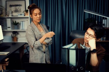 İş kadını, veri analizine işaret ederek, stresli iş arkadaşlarıyla birlikte gece geç saatlerde modern ofisteki fazla mesai şirketinde çalışmaya devam etmek için, çok çalışan proje işi klasörü evraklarına işaret ediyor. İnfobahn.