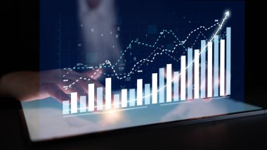 Bu resim, iş analitiği ve eğilimlerini temsil eden sanal grafikler ve veri görselleştirmeleri içeren bir tablet ekranın yer aldığı modern bir dijital çalışma alanını gösteriyor. Etki