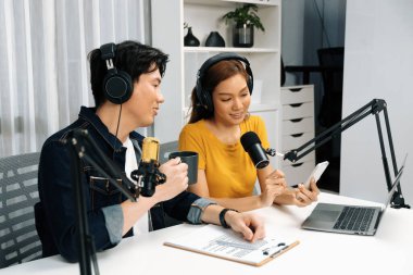 Gülümseyen radyo etkili sunucular, kulaklık takıp sosyal medyayı canlı yayında dinleyicilere telefon ve dizüstü bilgisayarla canlı yayınlıyorlar. İnfobahn.