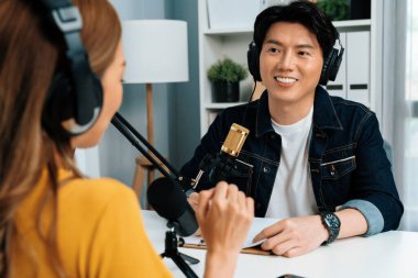 Gülümseyen radyo etkili sunucusu kulaklık takıyor kadın konuşmacı ile röportaj yapıyor sosyal medya internet sitesinden dinleyicilere bilgi paylaşıyor stüdyo kaydında sabah canlı yayın kanalı. İnfobahn.