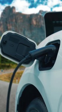 Elektrikli araç konsepti, yeşil çevre için yenilenebilir ve temiz enerjiyle çalışan EV otomobilinin varış noktasına ulaşmadan önce ormandaki şarj istasyonunun enerjisini şarj etmek için durur..