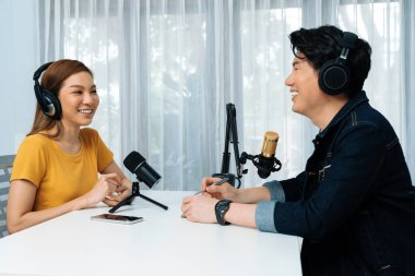 Gülümseyen radyo etkili sunucusu kulaklık takıyor kadın konuşmacı ile röportaj yapıyor sosyal medya internet sitesinden dinleyicilere bilgi paylaşıyor stüdyo kaydında sabah canlı yayın kanalı. İnfobahn.