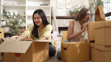 Çekici bir oda arkadaşı oturma odasında paket paketlerken pakette konum yazıyor. Mutlu satıcı birlikte çalışıyor ve teslimat paketini hazırlıyor. Girişimci kargo kutusu paketliyor. Myrmidon.