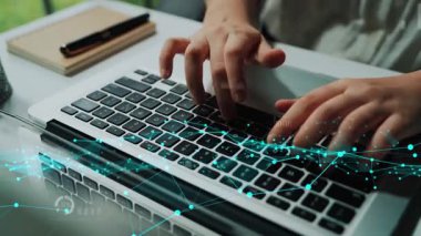 Modern bir ofiste iş analitiği ve içgörüyü temsil eden görsel dijital grafikler ve veri sembolleri olan bir dizüstü bilgisayar klavyesi üzerinde çalışan ellerin yakın çekimi. Xenic