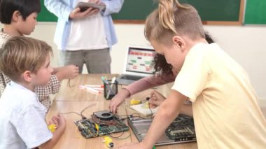Öğretmenler tablet verileri analiz ederken sevimli enerjik çocuklar elektronik panoda çalışıyor. Çeşitli öğrenci grubu ana tahtayı tamir ediyor ve yapay zeka ve programlama sistemini öğreniyor. Pedagoji.