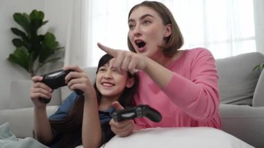 Kafkas anne ve kızı oturma odasında oturup oyun oynuyorlar. Mutlu anne, elinde joystick tutarken akıllı Asyalı kızla vakit geçiriyor. Oyun oynamaktan zevk alıyor. Yaşam tarzı konsepti. Pedagoji.