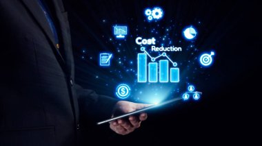 Bir işletme profesyoneli, maliyet azaltma ve veri analizi ile ilgili ikonları gösteren bir tabletle etkileşime girerek, modern ticarette mali planlamayı ve stratejik büyümeyi sembolize eder. Dörtgen
