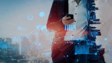 Bir iş adamı, modern teknoloji ve iş dünyasındaki bağlantıyı temsil eden grafikler ve şehir siluetinin yer aldığı soyut bir dijital manzara arasında akıllı telefon kullanır. Xenic