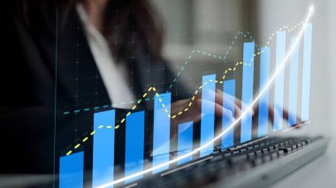 Dijital büyüme grafiklerini analiz ederken klavyeyle uğraşan bir iş adamının yakın plan görüntüsü, iş yerindeki finansal başarıyı ve stratejik sezgileri sembolize ediyor. Copula