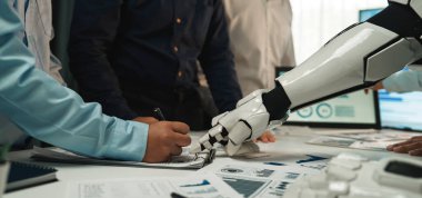 Teknolojinin modern çalışma alanlarına entegrasyonunu vurgulayan, ortak bir iş toplantısında bir insana yardım eden robot kolunu gösteren dinamik bir sahne. Noogenesis